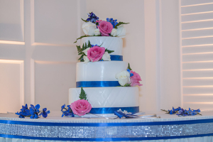 Beautiful wedding cake with pink and white rose decor and blue ribbon